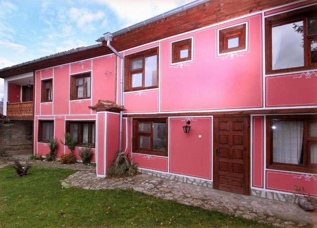 un edificio rosa con un patio delante en Nenchova Guest House, en Koprivshtitsa