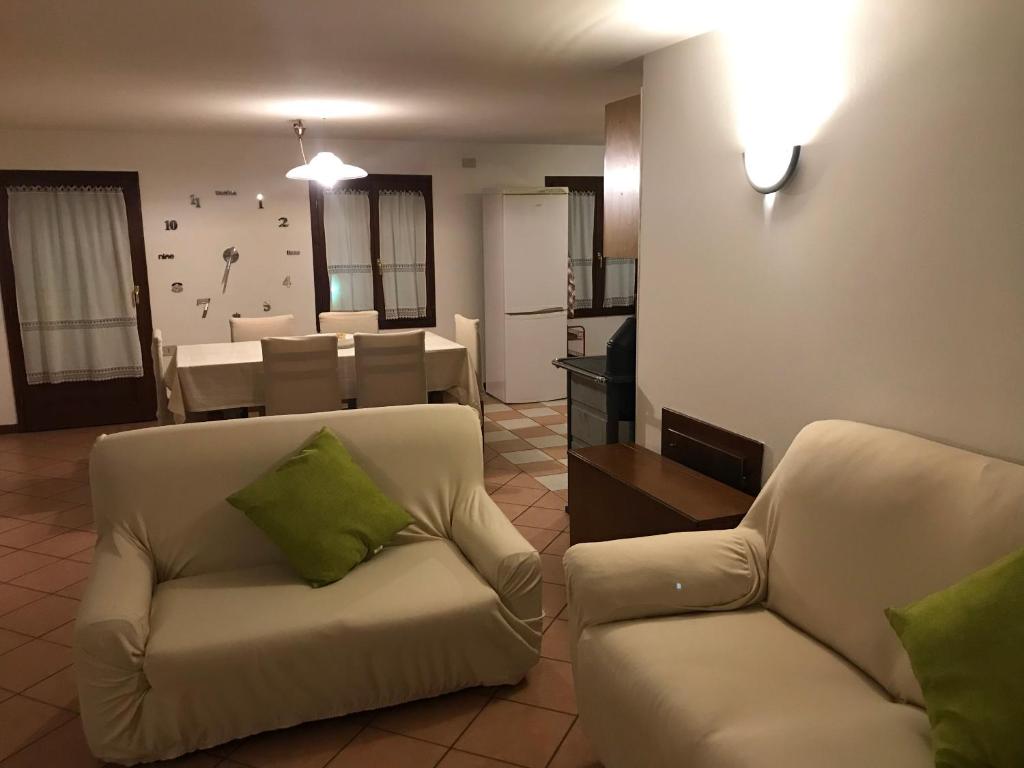 sala de estar con 2 sillas blancas y cocina en Casa Cortese en Gallio