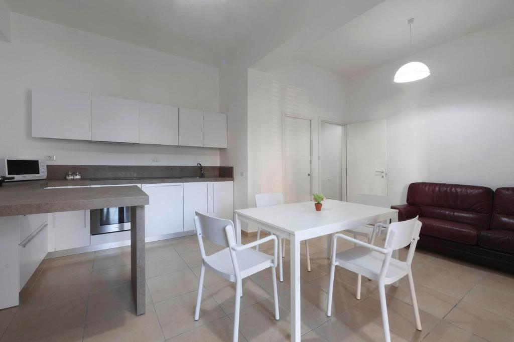 a kitchen and dining room with a white table and chairs at Apartments d'Orlando - 2 bedrooms apartment with garden in Capo dʼOrlando