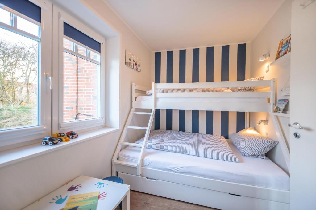 a bunk bed room with two bunk beds and a ladder at Dünenstern in Wangerooge