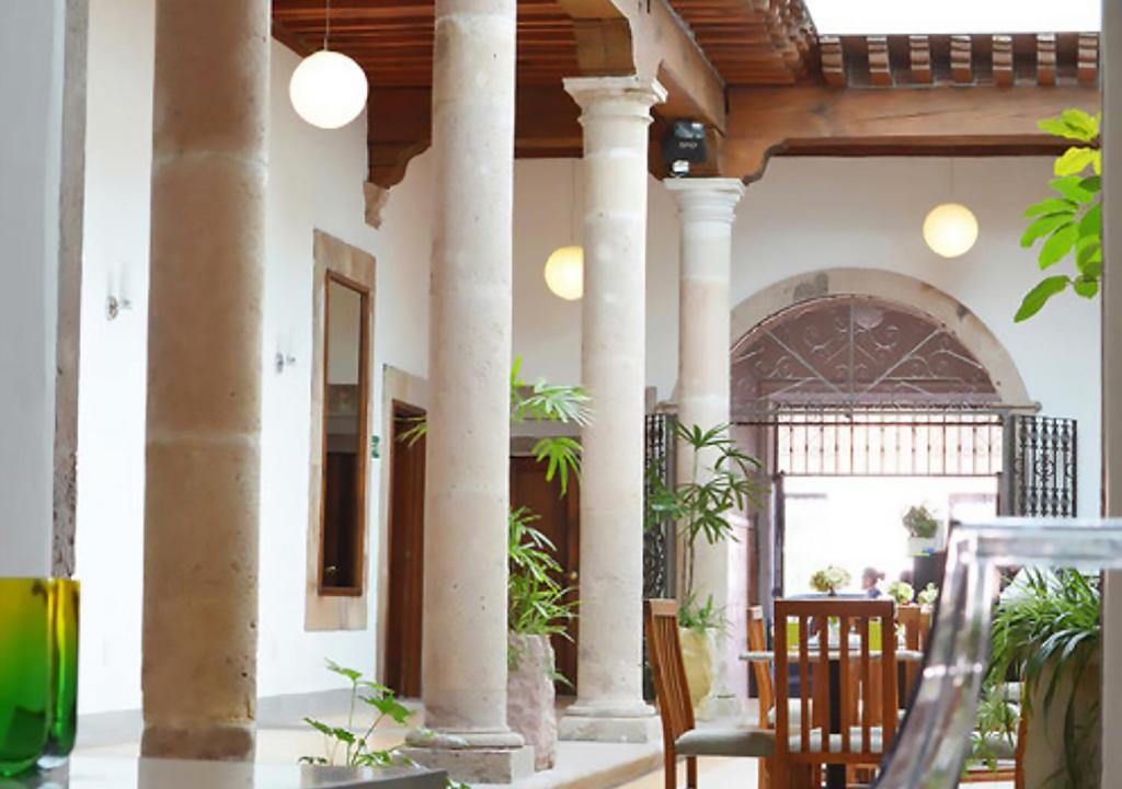 un edificio con columnas, mesa y sillas en Hotel Expres By Hosting House, en Morelia