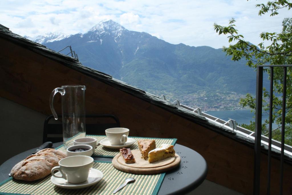 un tavolo con due piatti di cibo su un balcone con vista sulle montagne di Rifugio Dalco a Sorico