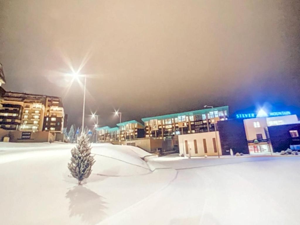 a small christmas tree in the snow in front of a city at Silver Mountain Apartment in Poiana Brasov