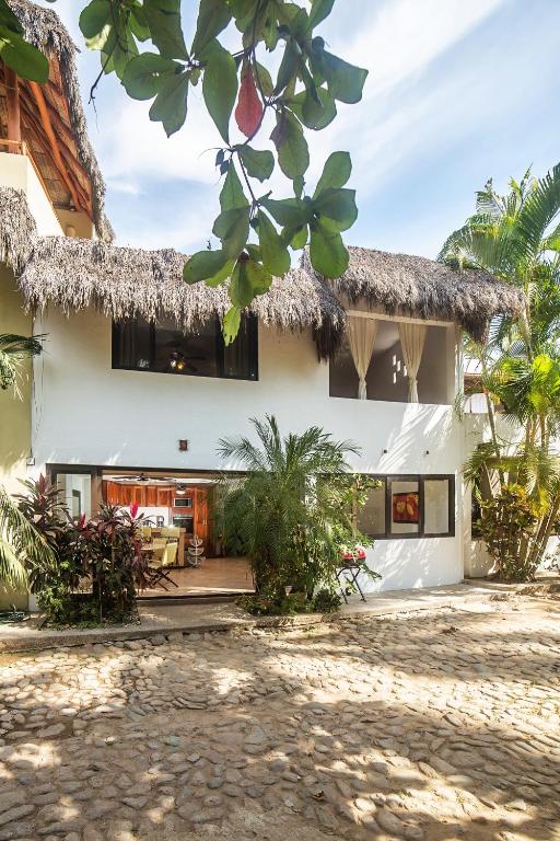 a house with a thatched roof and a courtyard at Casa Silvana - Villas del Palmar in Sayulita