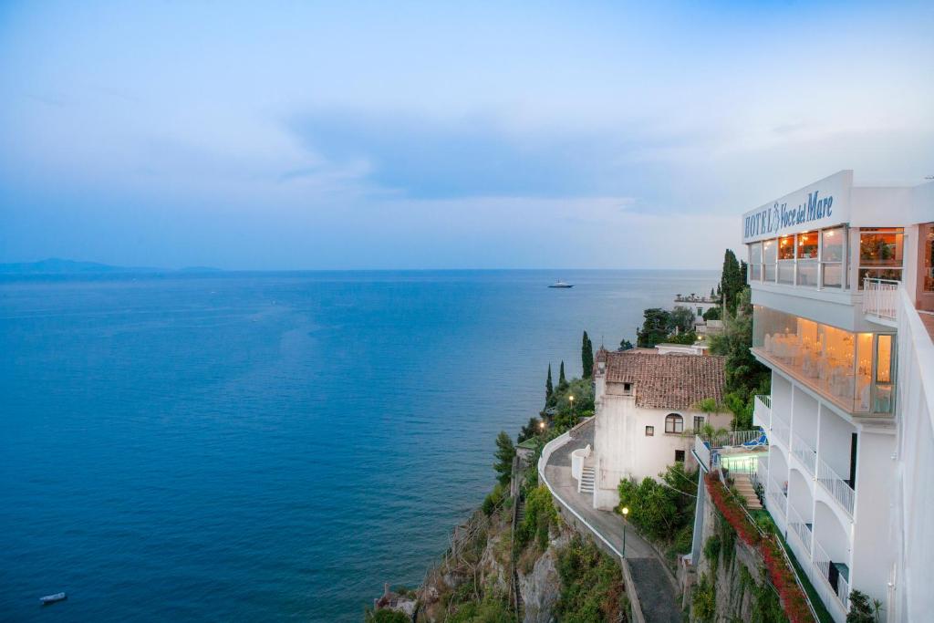a building on a cliff next to the water at Hotel Voce del Mare in Vietri sul Mare