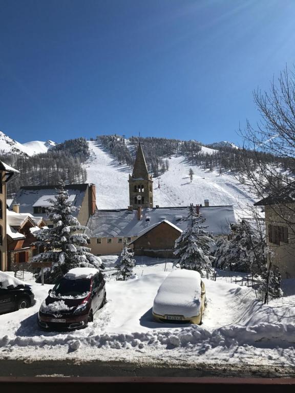 a church with snow covered cars parked in a parking lot at Appartement dans chalet in Montgenèvre