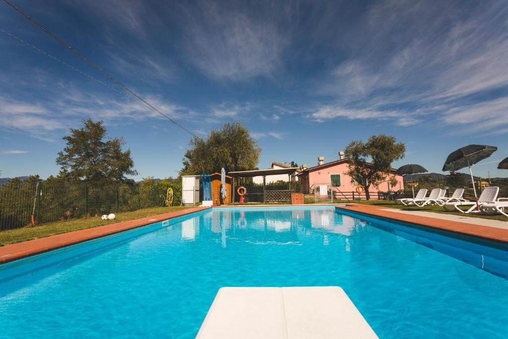 a large blue swimming pool with chairs and a house at Agriturismo Daniela in Bracelli