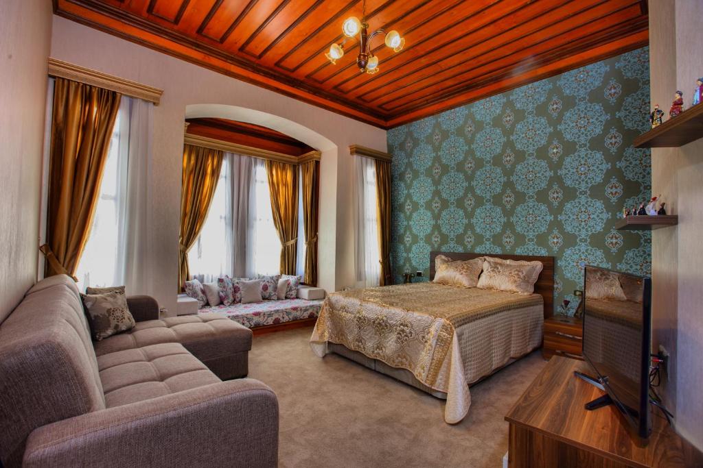 a bedroom with a bed and a couch and a tv at The Pashas House in Istanbul
