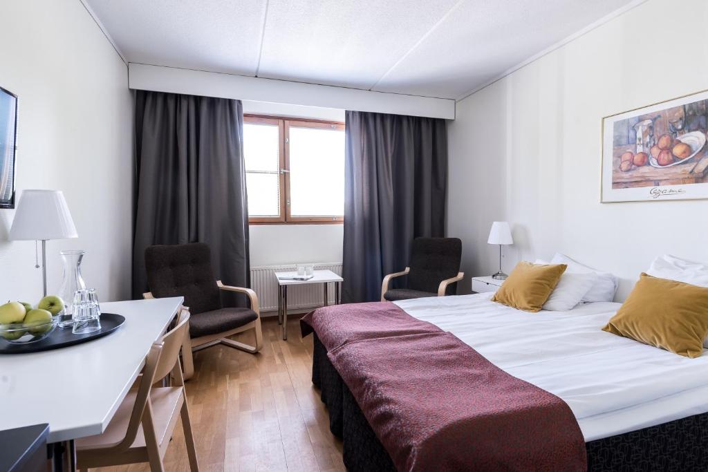 タンペレにあるHotel Hermicaのベッド、テーブル、椅子が備わるホテルルームです。