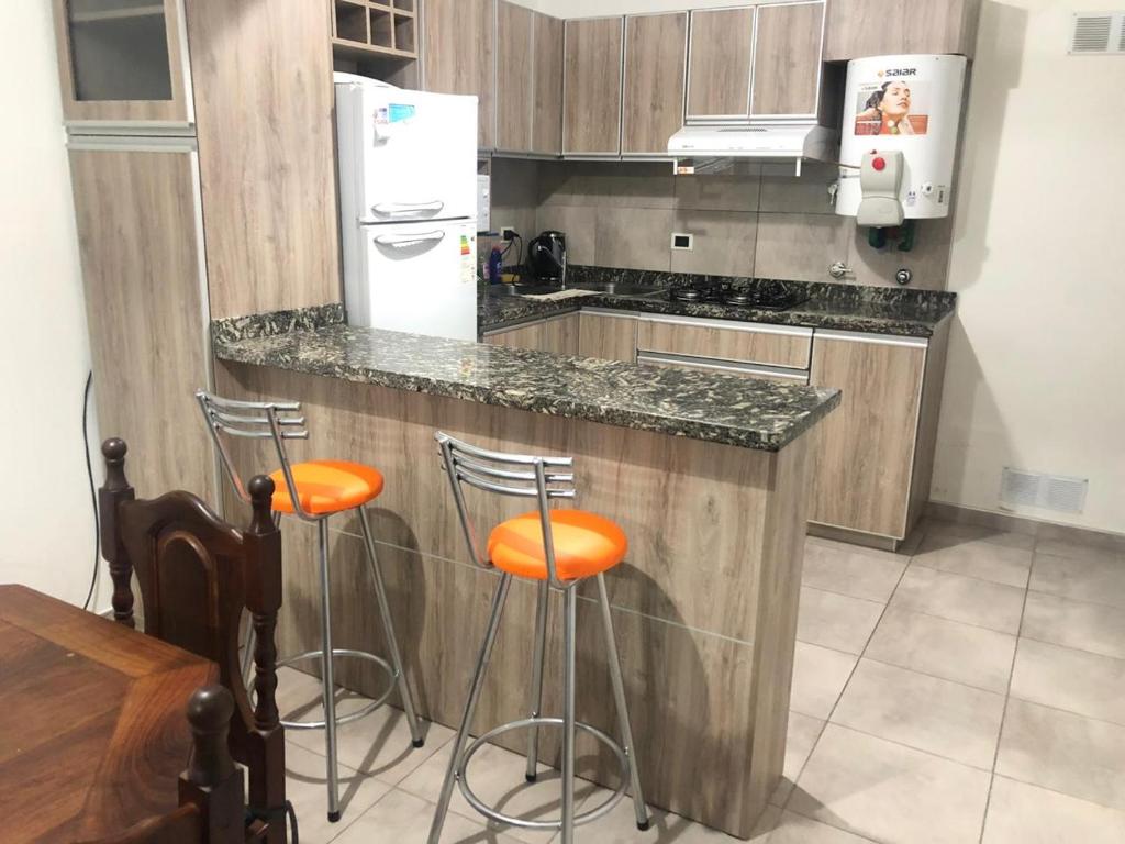 een keuken met een aanrecht met krukken en een koelkast bij Los Talas in Villa Carlos Paz