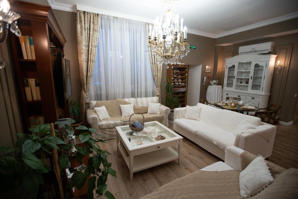 a living room with white furniture and a chandelier at Boutique Hotel Dubrovskiy in Sergiyev Posad