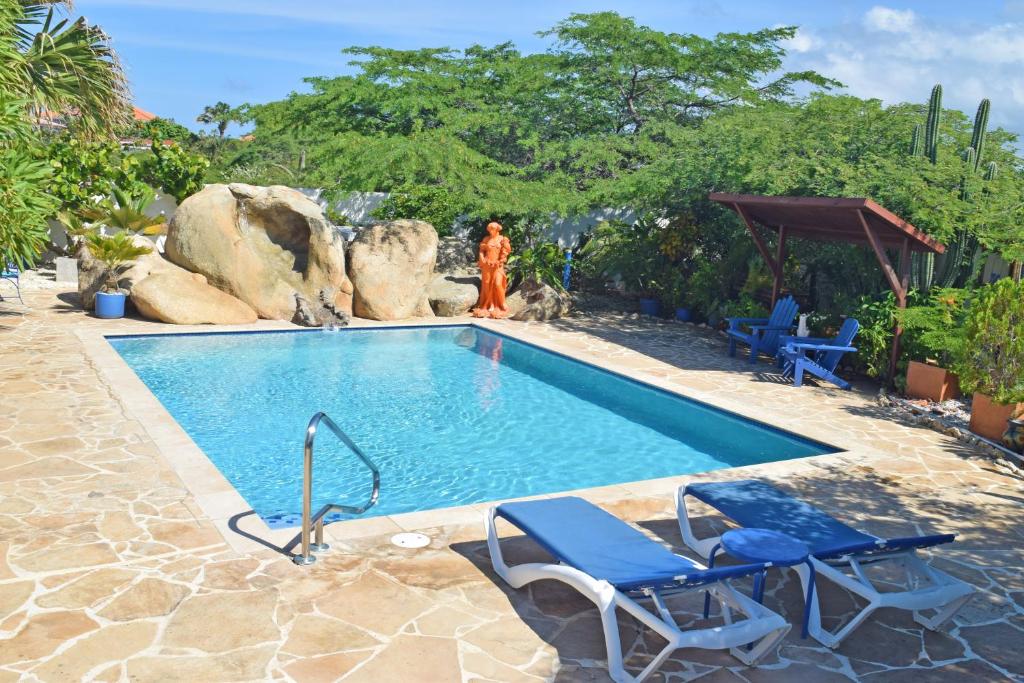 una piscina con dos sillas y una mujer de pie junto a ella en Villa Bougainvillea Aruba Rumba Suite, en Palm-Eagle Beach