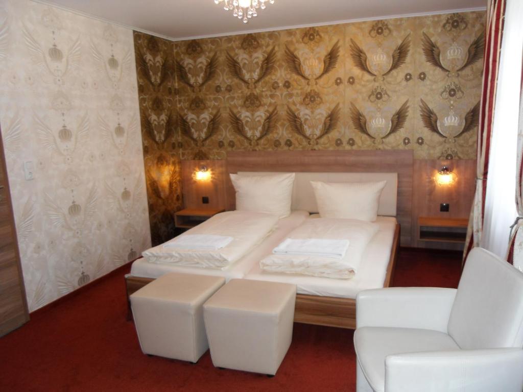 a bedroom with a white bed and two white chairs at Landhotel Fuchsbau in Vohenstrauß