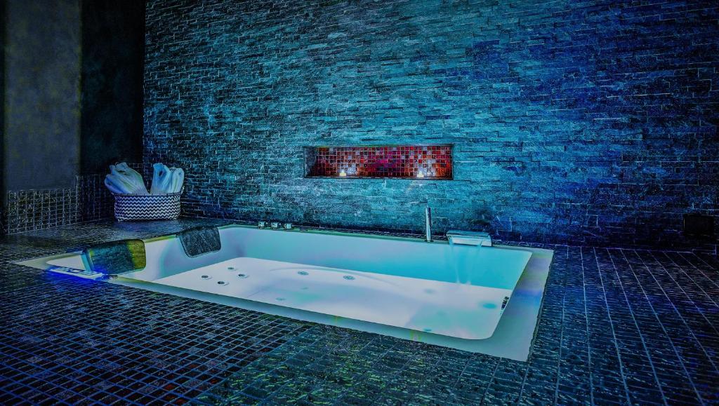 a bath tub in a room with a brick wall at Suite Romantique in Narbonne