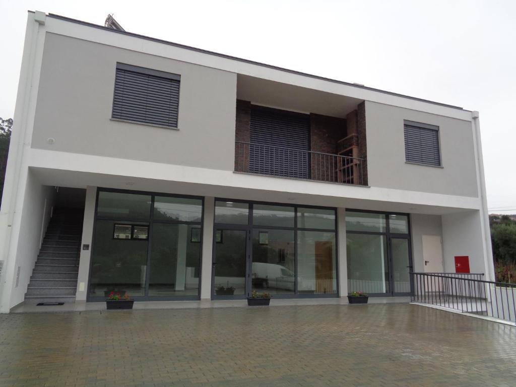 un grand bâtiment blanc avec de grandes fenêtres en verre dans l'établissement Charrua do Mondego - Alojamento Local, à Penacova