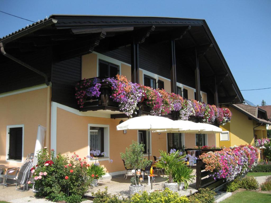 un edificio con flores en un balcón con sombrilla en Gästehaus Stroitz, en Drobollach am Faakersee