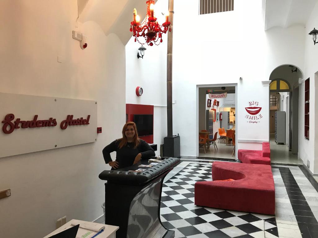 une femme assise dans un bar dans une pièce avec des chaises rouges dans l'établissement Student’s Hostel, à Montevideo