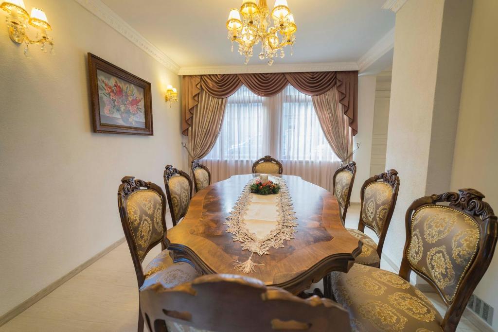 ein Esszimmer mit einem Tisch, Stühlen und einem Kronleuchter in der Unterkunft Ikonomov House in Bansko