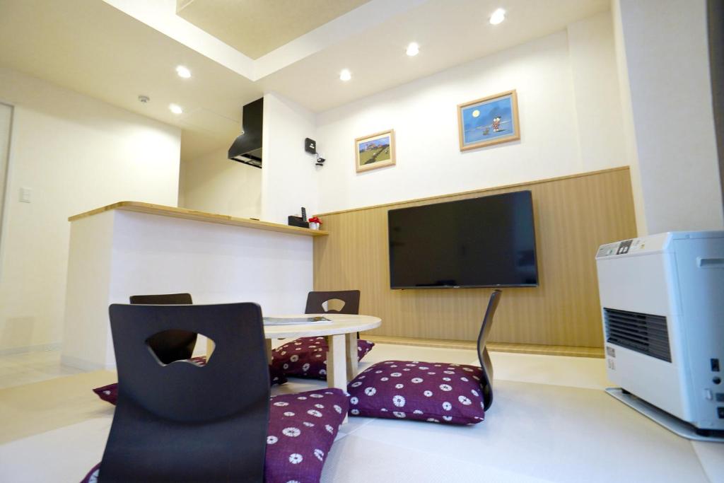 Habitación con mesa, sillas y TV. en momo premium 403, en Sapporo