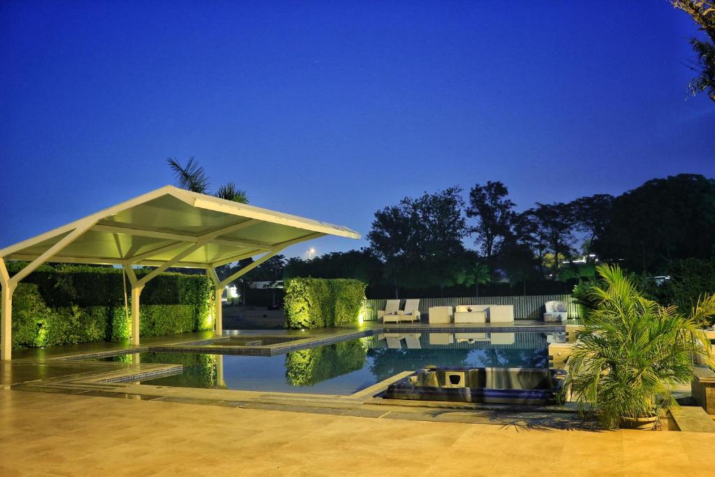 a house with a swimming pool and a pavilion at Satvik Resort in New Delhi