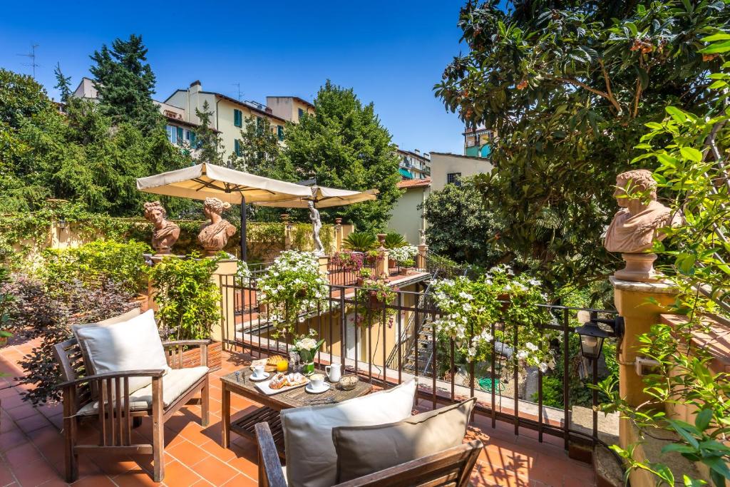 eine Terrasse mit einem Tisch, Stühlen und einem Sonnenschirm in der Unterkunft Hotel Ungherese Small Luxury Hotel in Florenz