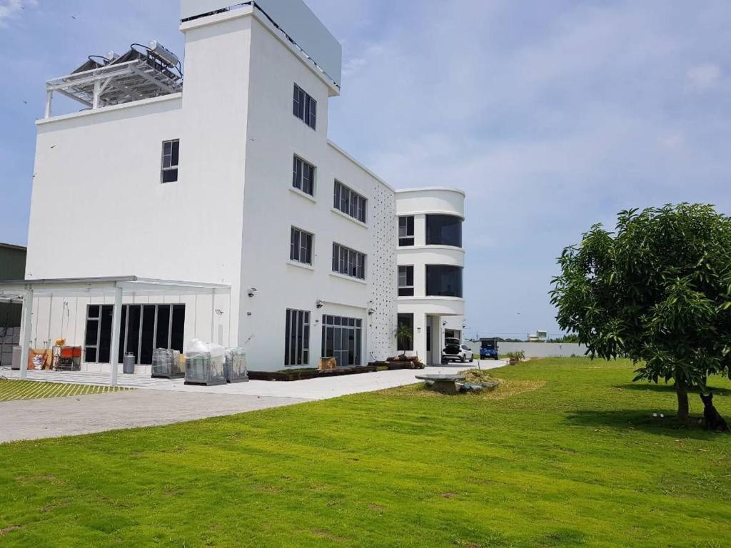 a large white building with a green field in front of it at White Hunter B&B in Tainan