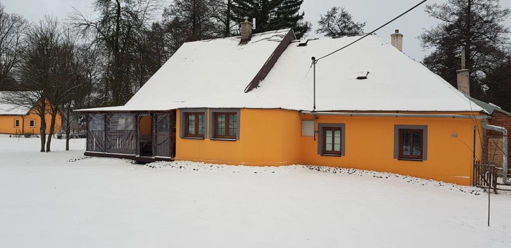 a yellow house with snow on the roof at Chata Na Kovárně in Rýmařov