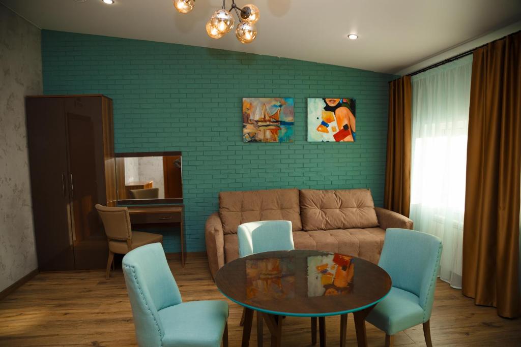 ein Wohnzimmer mit einem Sofa, einem Tisch und Stühlen in der Unterkunft Гостиница "Аристократ" in Krasnojarsk