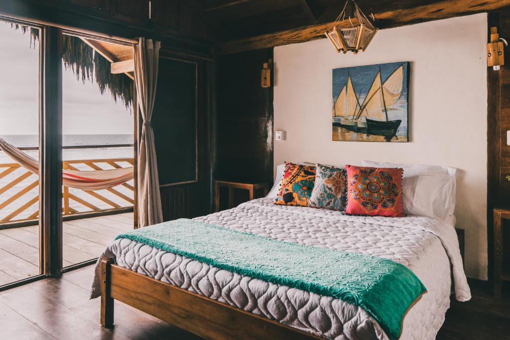 Un dormitorio con una cama con almohadas y una pintura en Cuna Luna Hosteria, en Olón