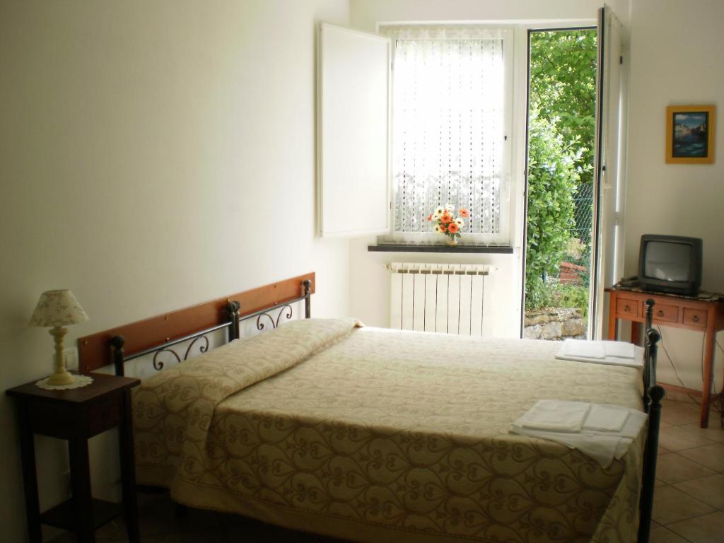 1 dormitorio con cama, ventana y TV en Hotel Paese Corvara, en Beverino