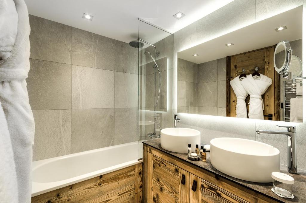 a bathroom with two sinks and a tub and a mirror at Hôtel La Sivolière in Courchevel