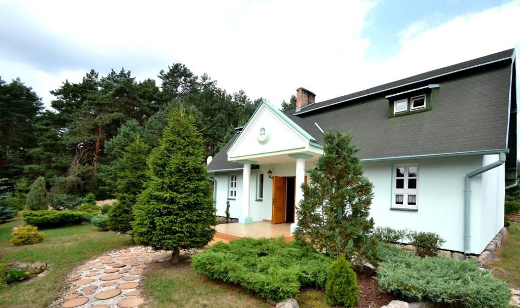 een wit huis met een tuin met bomen bij Dworek Drawa in Drezdenko