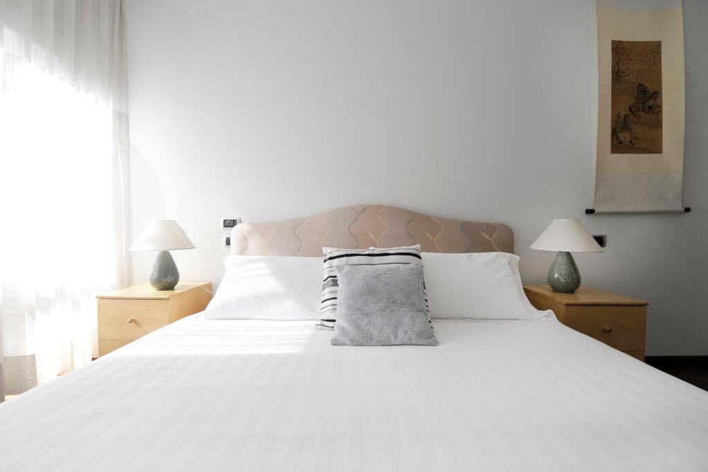 una camera da letto con un grande letto bianco con due lampade di In+out Sempione Park Apartment a Milano