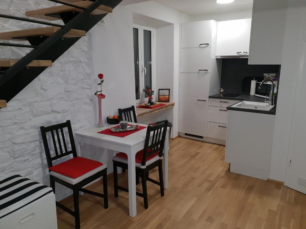 une cuisine avec une table blanche et deux chaises dans l'établissement Stone Wall Apartment Izola, à Izola