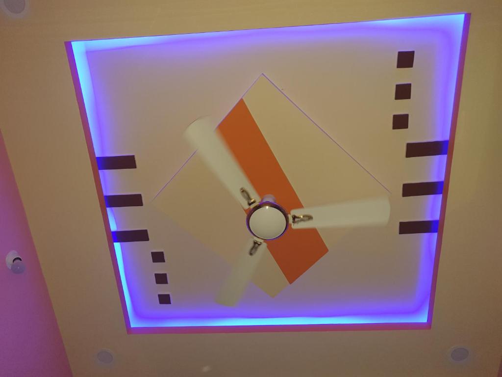a purple light on a wall with a ceiling fan at Rks Homestay in Hampi