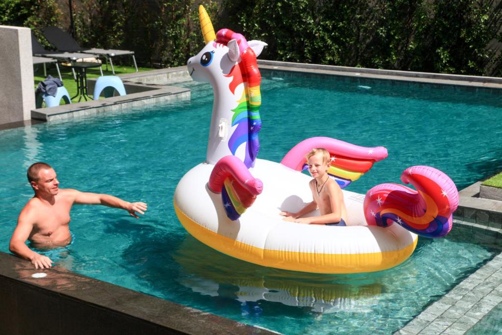 a man and a woman in a swimming pool with an unicorn inflatable at The Glory Gold in Khao Lak