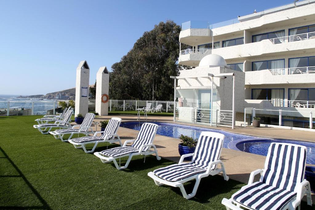 uma fila de cadeiras de jardim em frente a um edifício em MR Mar Suites (ex Neruda Mar Suites) em Viña del Mar