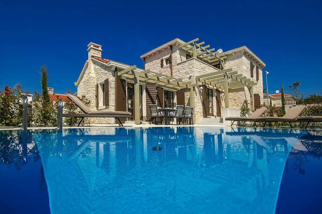 une grande piscine en face d'une maison dans l'établissement Luxury Stone Villa Zanelli, à Ližnjan