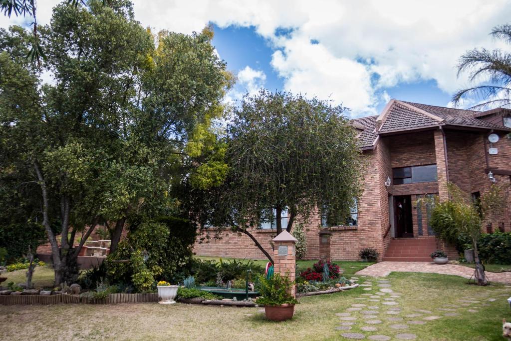 una casa de ladrillo con árboles en el patio en Jenny's Guest House, en Grahamstown