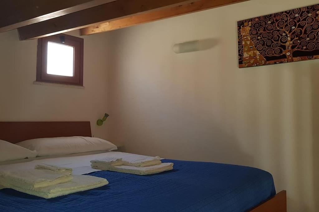 una camera da letto con un letto con lenzuola blu e una finestra di La perla sul golfo a Castellammare del Golfo