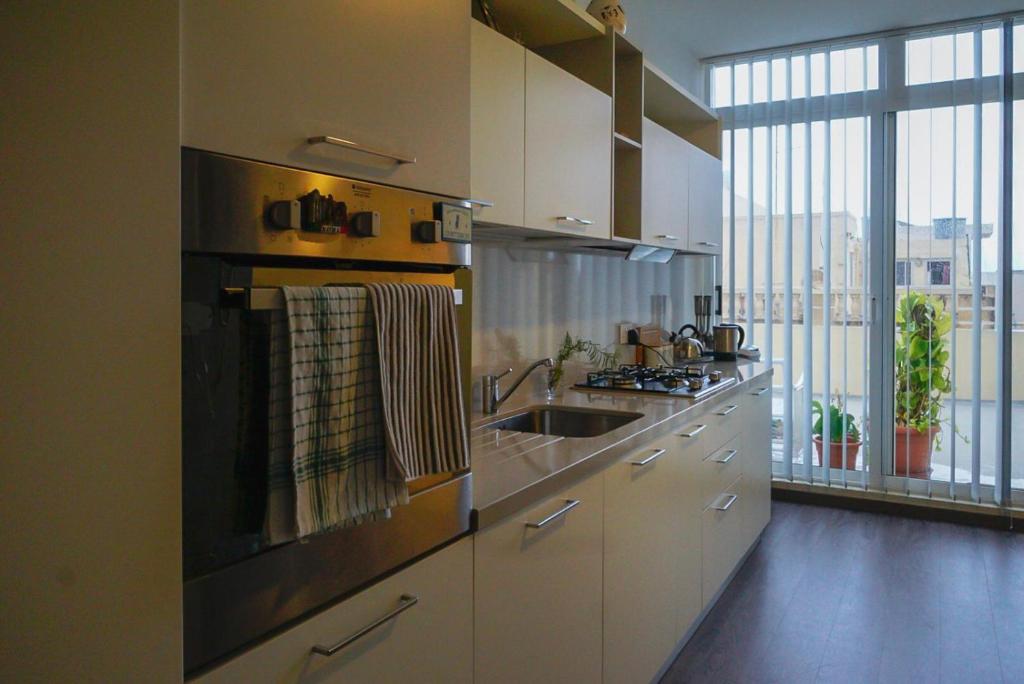 uma cozinha com um lavatório e um fogão forno superior em Cosy Home by the Sea em Birzebbuga