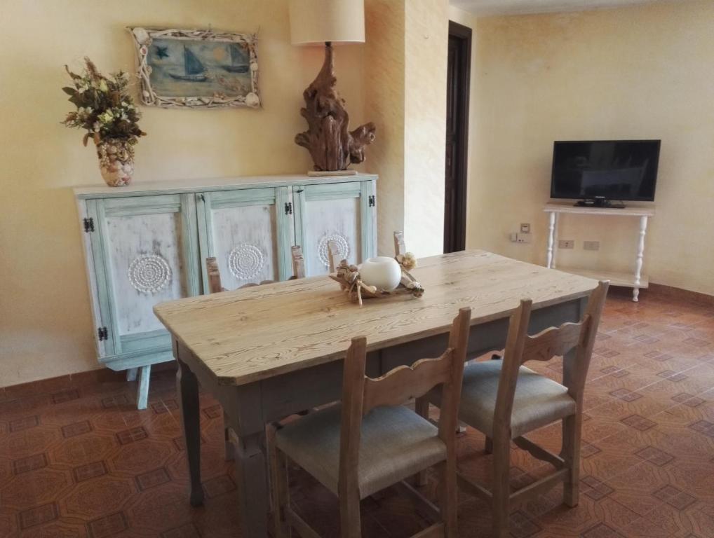 comedor con mesa de madera y sillas en Appartamento Villa Edera, en Baja Sardinia