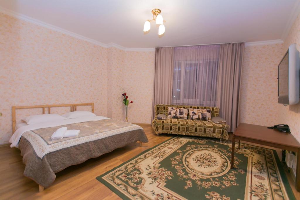 ein Schlafzimmer mit einem Bett, einem Sofa und einem TV in der Unterkunft Apartment on Sarayshyq in Astana