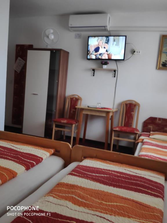 a hotel room with two beds and a flat screen tv at Herkules Panzió in Nagykanizsa