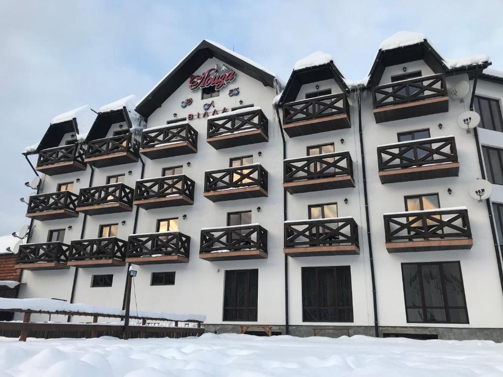 a white building with black balconies in the snow at Villa Loiza in Bukovel