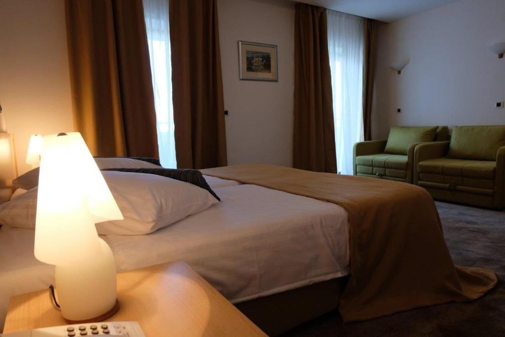a hotel room with two beds and a table with a lamp at Hotel Flores in Poreč
