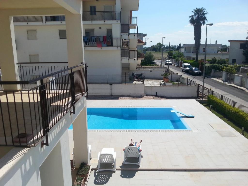 a person laying on a balcony next to a swimming pool at Lina Apartments C1 in Ginosa Marina