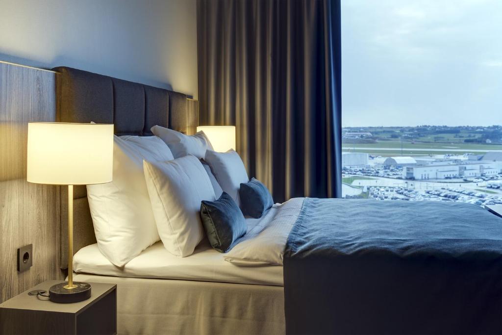 Habitación de hotel con cama con almohadas y ventana en Clarion Hotel Air, en Sola