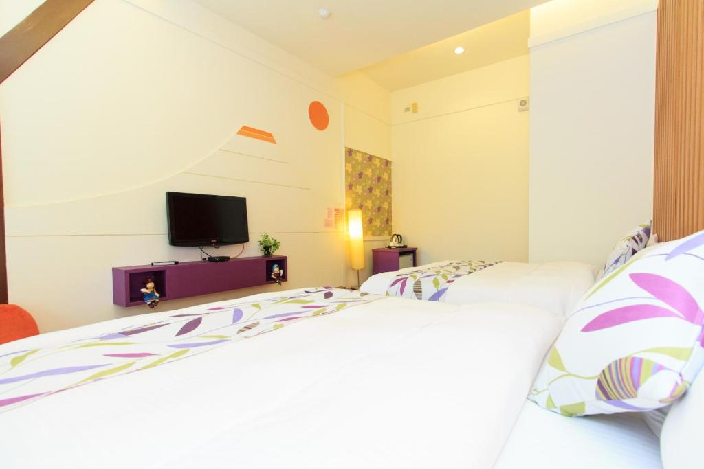 a bedroom with two beds and a tv at Lotus Hostel Beicheng Zhuang in Luodong