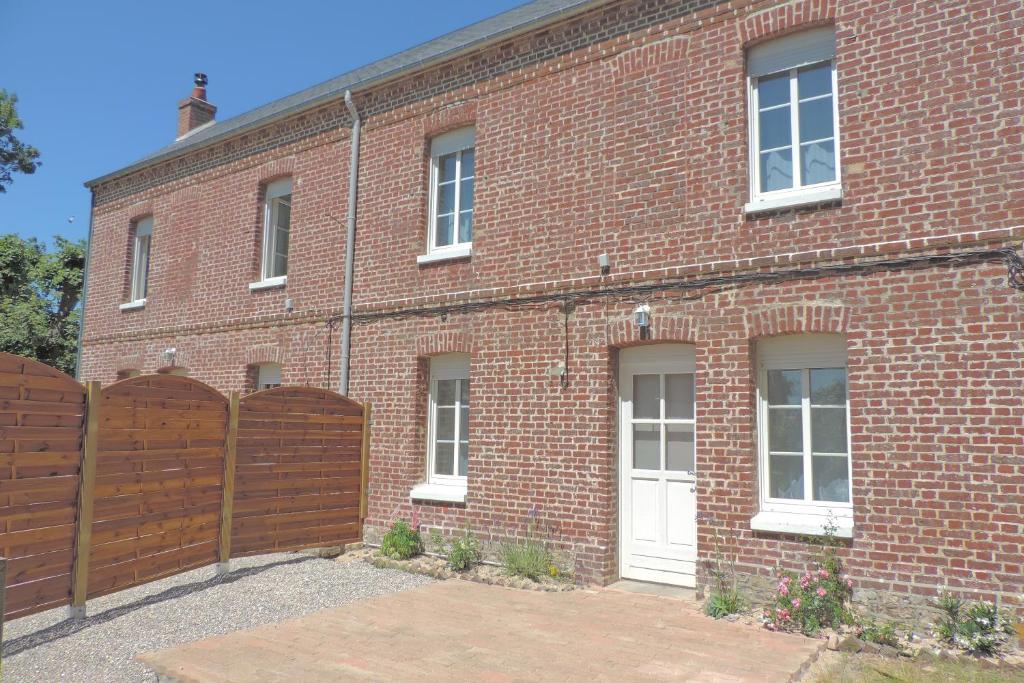 un bâtiment en briques avec une clôture en bois devant lui dans l'établissement Belval Cottages, à Bénouville